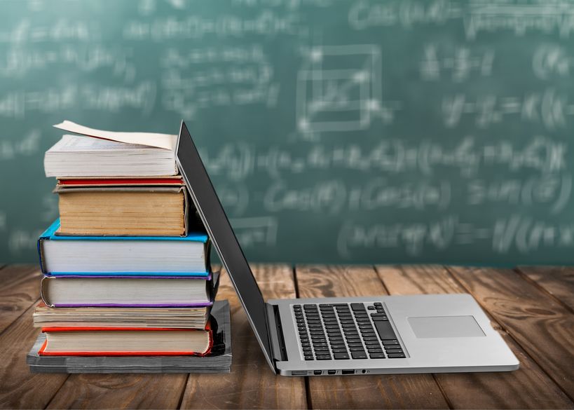 Stack of books with laptop on table